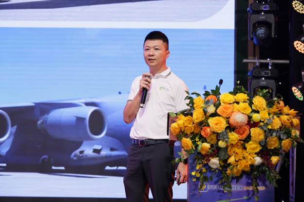 A person standing on a stage with a microphone and a bunch of flowersAI-generated content may be incorrect.