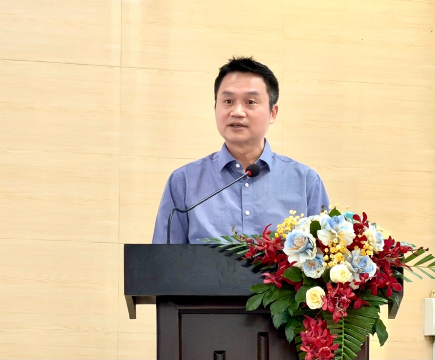 A person standing at a podium with a microphone and flowersAI-generated content may be incorrect.