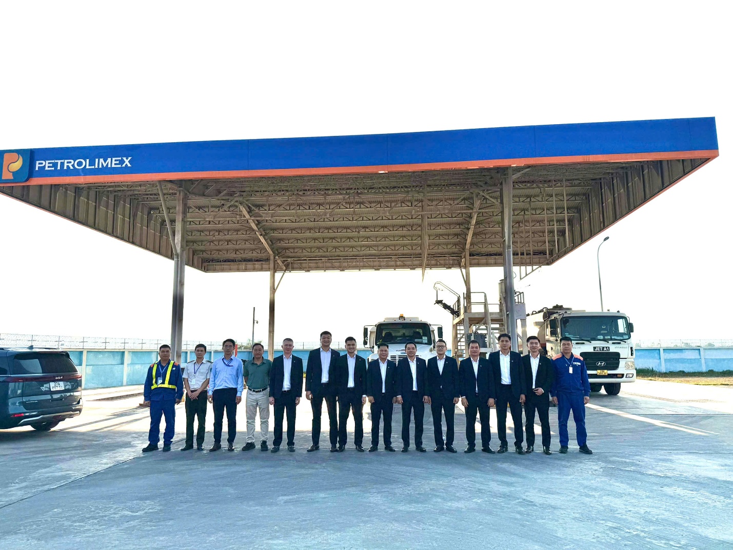 A group of people standing in front of a gas stationDescription automatically generated